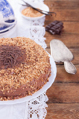 Chocolate truffle cake with сrushed peanuts and cacao on a wooden background. Selective focus..