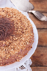 Chocolate truffle cake with сrushed peanuts and cacao on a wooden background. Selective focus.