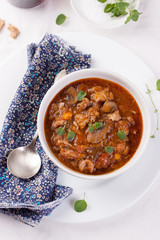 Chicken ragout with pumpkin, mushrooms and oregano stewed in red wine in a white ceramic bowl. Top view.