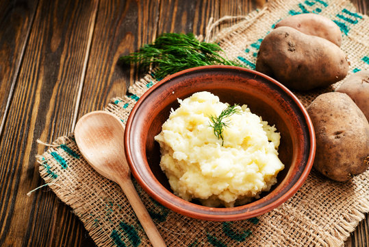 
mashed boiled potato with herbs. milk and spices on a wooden background