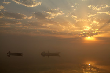 Fototapeta na wymiar Boats in foggy sunrise
