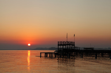 Naklejka na ściany i meble Beautiful sun and the silhouette of wooden platform at sunrise