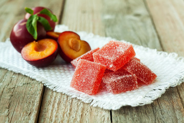 Homemade plum jelly and plums on wood table