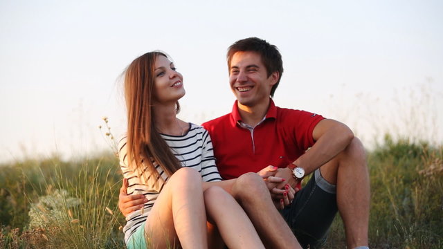 Young couple sitting together at the sunset