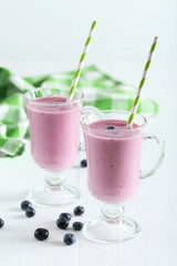 Fresh blueberry smoothie in the glasses on white wooden backgrou