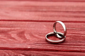 Silver wedding rings on a red wooden table