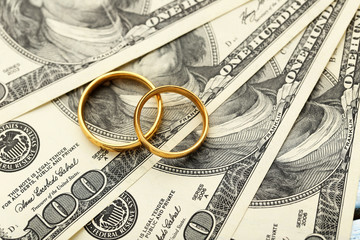 Golden wedding rings on one hundred dollars bill background