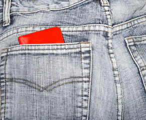 Red wallet in a hip-pocket of blue jeans