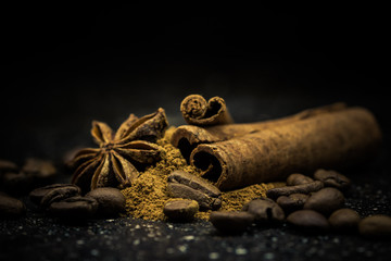 Star anise, cinnamon, coffe and ground cinnamon on a black marble slab