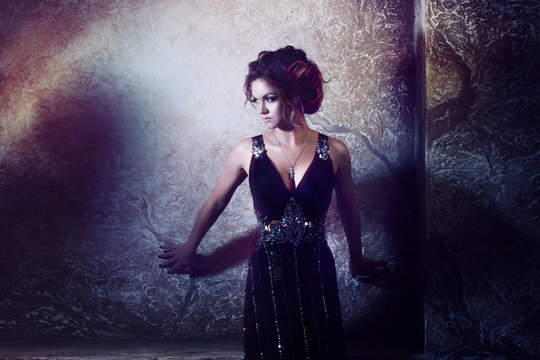 young beautiful woman in long dress against the wall,  dark style,  mysterious atmosphere