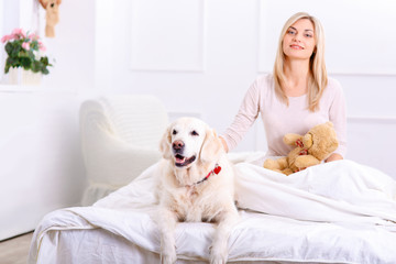 Caring woman lying on bed with her dog 