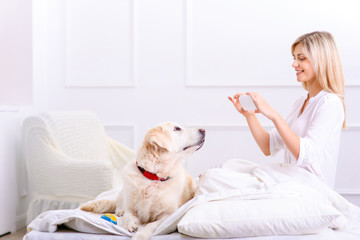 Caring woman lying on bed with her dog 