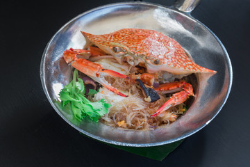 Casseroled crab with glass noodles on black background