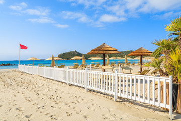 Sunchairs and umbrellas with white wooden fence at Porto Giunco beach, Sardinia island, Italy