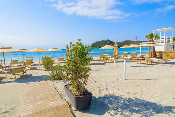 Sunchairs and umbrellas with white wooden lifeguard tower at Porto Giunco beach, Sardinia island, Italy