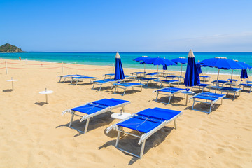 Fototapeta na wymiar Sun beds with umbrellas on sandy Costa Rei beach, Sardinia island, Italy