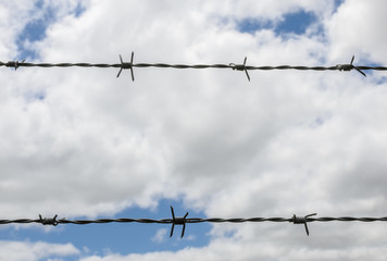 barbed wire fence with clouds in sky in background
