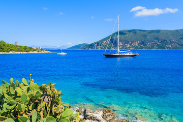 Fototapeta na wymiar Luxury yacht boat on blue sea with green cacti plants in foreground on coast of Kefalonia island near Fiskardo village, Greece