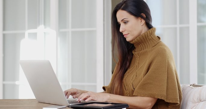 Attractive woman sitting typing on a laptop