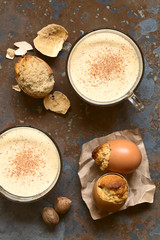Eggnog cupcakes baked in eggshell and eggnog drink in glass cups, photographed overhead with natural light (Selective Focus, Focus on the top of the cupcakes and the drinks)