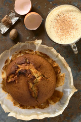 Eggnog cake baked in round form with eggnog drink on the side, photographed overhead on slate with natural light (Selective Focus, Focus on the cake and the drink)