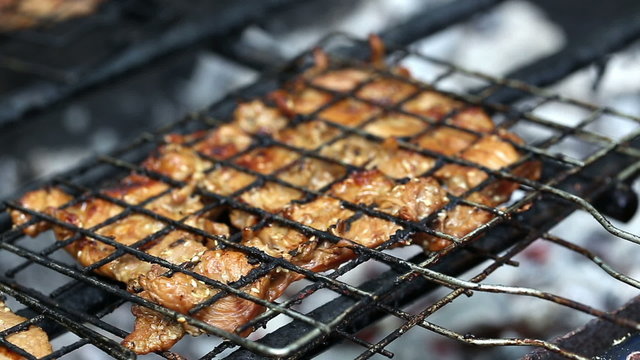 pork chops getting grilled on grill with flames.