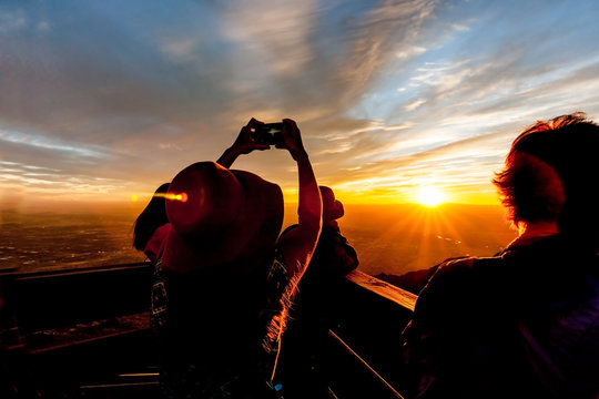 Tourists silhouetted watch and photograph brilliant New Mexico sunset