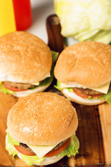 Hamburgers with cheese, potato chips and ingredients on a white background