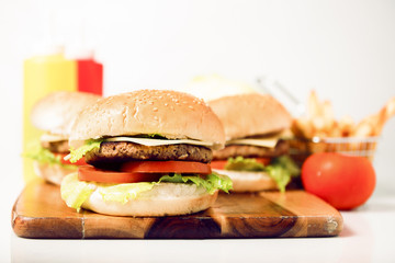 Hamburgers with cheese, potato chips and ingredients on a white background