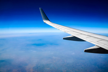 Fototapeta premium Wing of airplane flying above the clouds in the sky