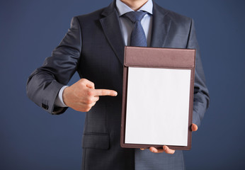 Businessman holding a clipboard with blank and indicating it