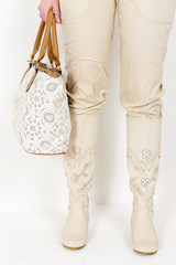 detail of standing woman wearing summer boots holding a handbag