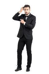 Stubble wealthy luxurious man combing his hair looking away. Full body length portrait isolated over white studio background.