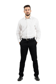 Confident elegant business man with hands in pockets looking at camera.  Full body length portrait isolated over white studio background.