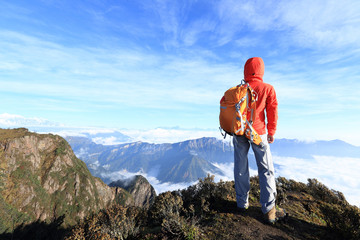 young determined woman backpacker hiking on mountain peak