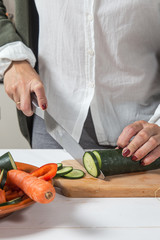 Woman cutting vegetables on wooden board