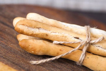 Salted Italian grissini on wooden cutting board close up