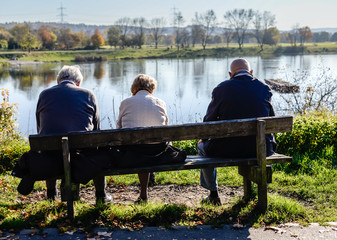 Eine Gruppe von Senioren ruht sich auf einer Parkbank aus. 