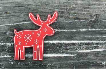 Red deer with white snowflakes and snowdrifts on an old wooden b