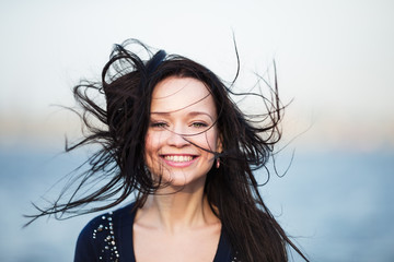 Smiling girl with long black hair blowing by wind