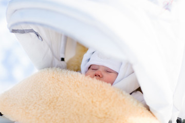Newborn baby boy sleeping in stroller in winter