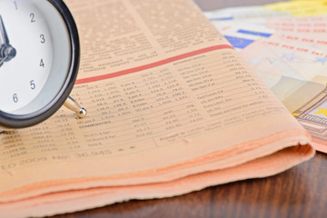 Close-up of clock, Euro banknotes and newspaper