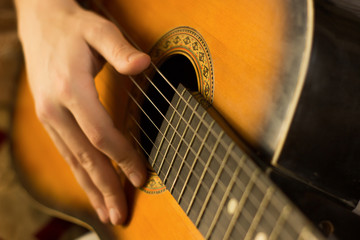 Fototapeta premium Young guy playing on guitar. Hand and guitar close-up.Soft and blur conception