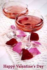 Composition with pink sparkle wine in glasses and rose petals