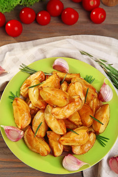 Baked potato wedges on wooden table, top view