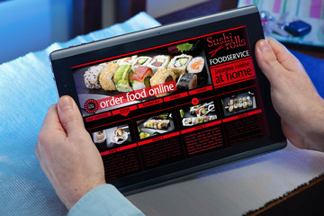 hands of a man in a website of a restaurant food delivery service in the tablet /man searching...