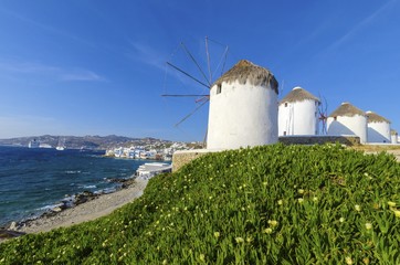 Four windmills in Chora,Mykonos,Greece.Traditional greek whitewashed architecture,popular landmark,tourist destination against blue sky and Aegean sea over Little Venice.Wind mills are now decorative. © f8grapher