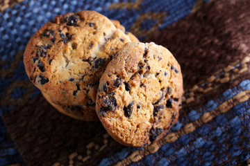 Cookies with chocolate crumbs on ornament napkin against blurred background, close up