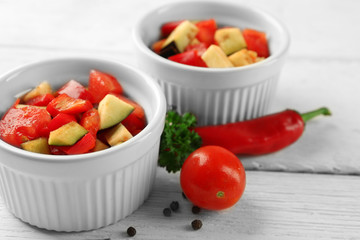 Ratatouille, stewed vegetable dish with tomatoes, zucchini, eggplant before cooking, on wooden background