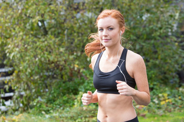 Fototapeta premium redhead woman running outsdie on a trail